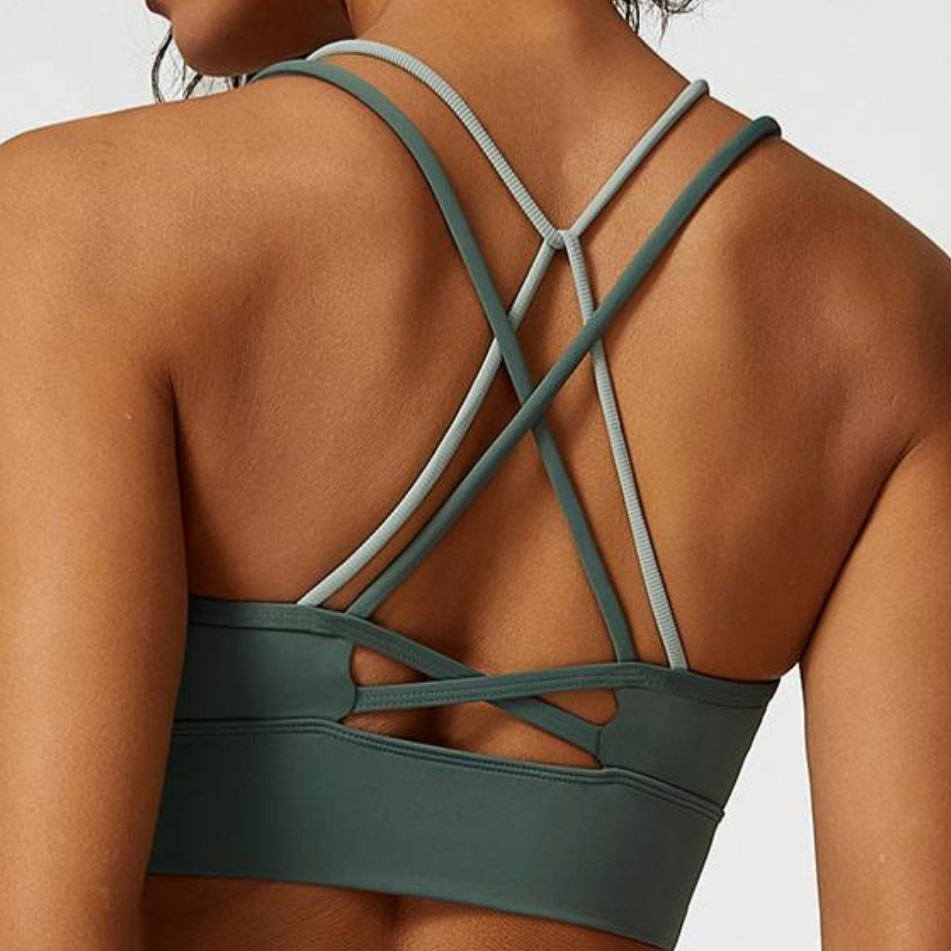 Green sports bra with criss-cross straps on a neutral background