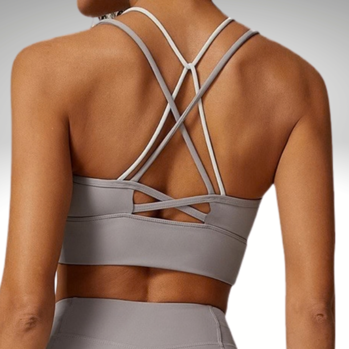 Gray sports bra with criss-cross straps on a neutral background